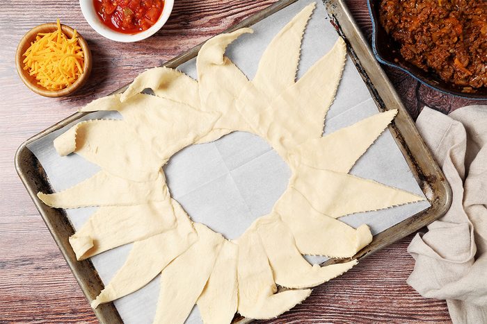 Taco Ring shot on a brown wooden surface, Crescent roll dough layed out on a baking sheet;