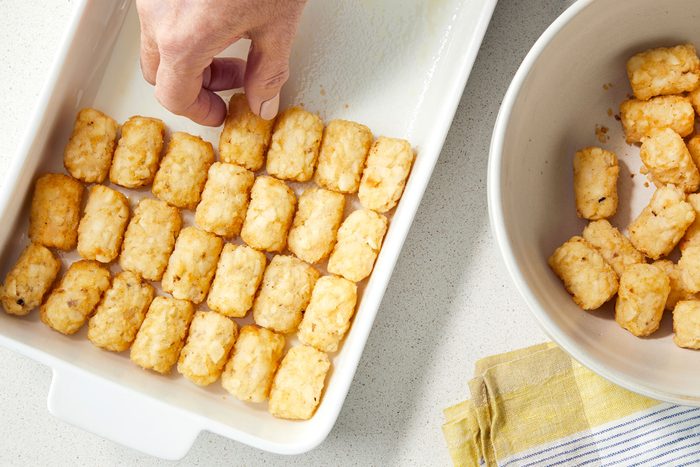 Lining the bottom of greased baking dish with Tater Tots