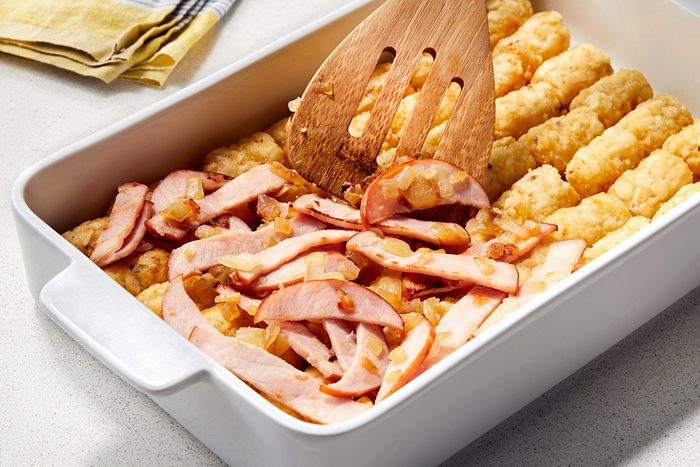 Topping the Tater Tots with canadian bacon mixture