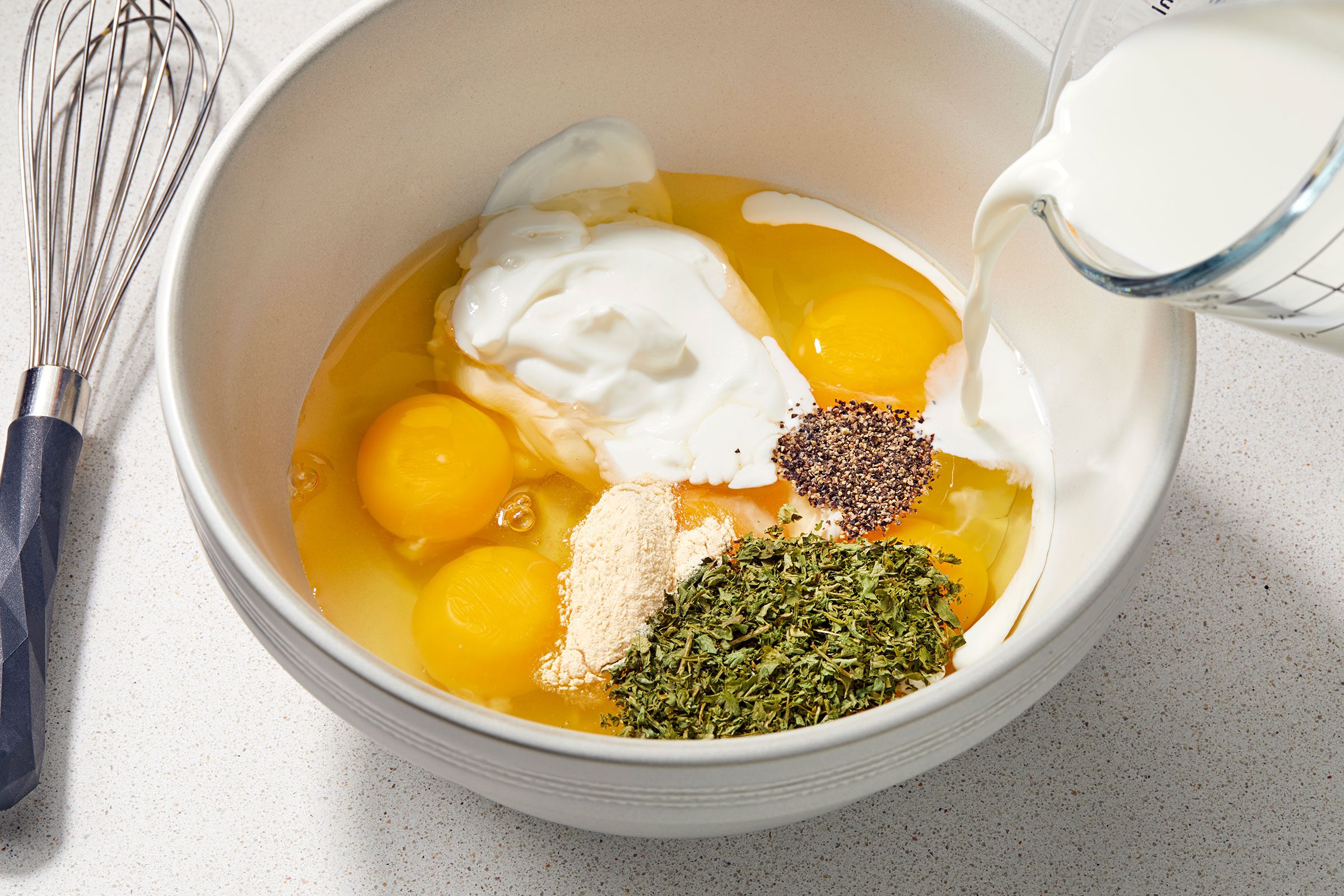 Eggs, sour cream and seasonings in a white bowl 
