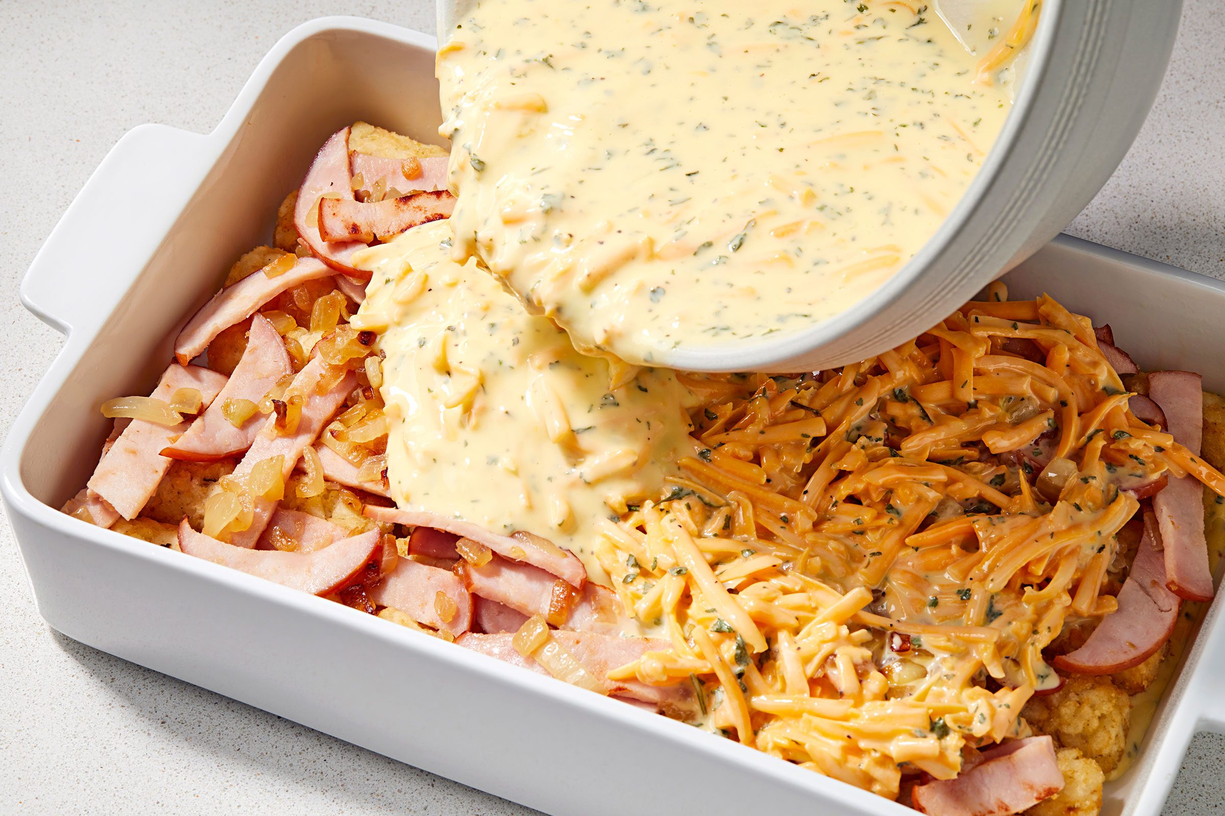 Egg cream mixture poured on layered Tater Tots in a baking dish