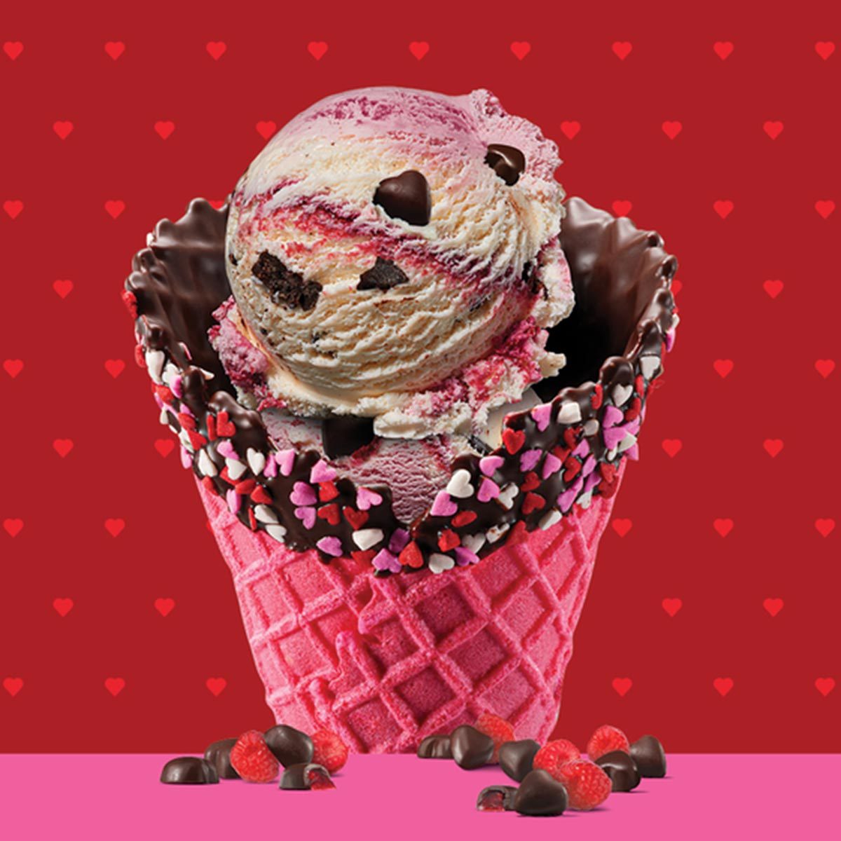Baskin Robbins love potion ice cream scoop in a chocolate-dipped, sprinkle-coated, pink cone on a red background with a small pink heart pattern