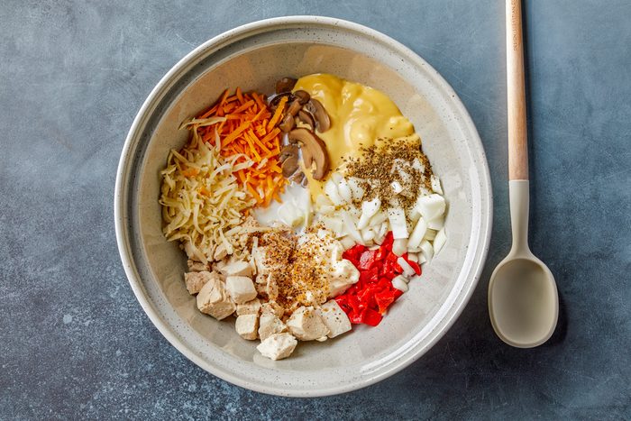 in a large bowl, combine the chicken, soup, milk, onion, 1/2 cup cheddar cheese, 1/2 cup Swiss cheese, mushrooms, peppers, mayonnaise, steak seasoning and basil.