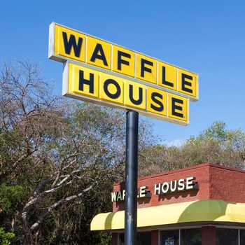 Yellow and black Waffle House sign in front of a Waffle House restaurant