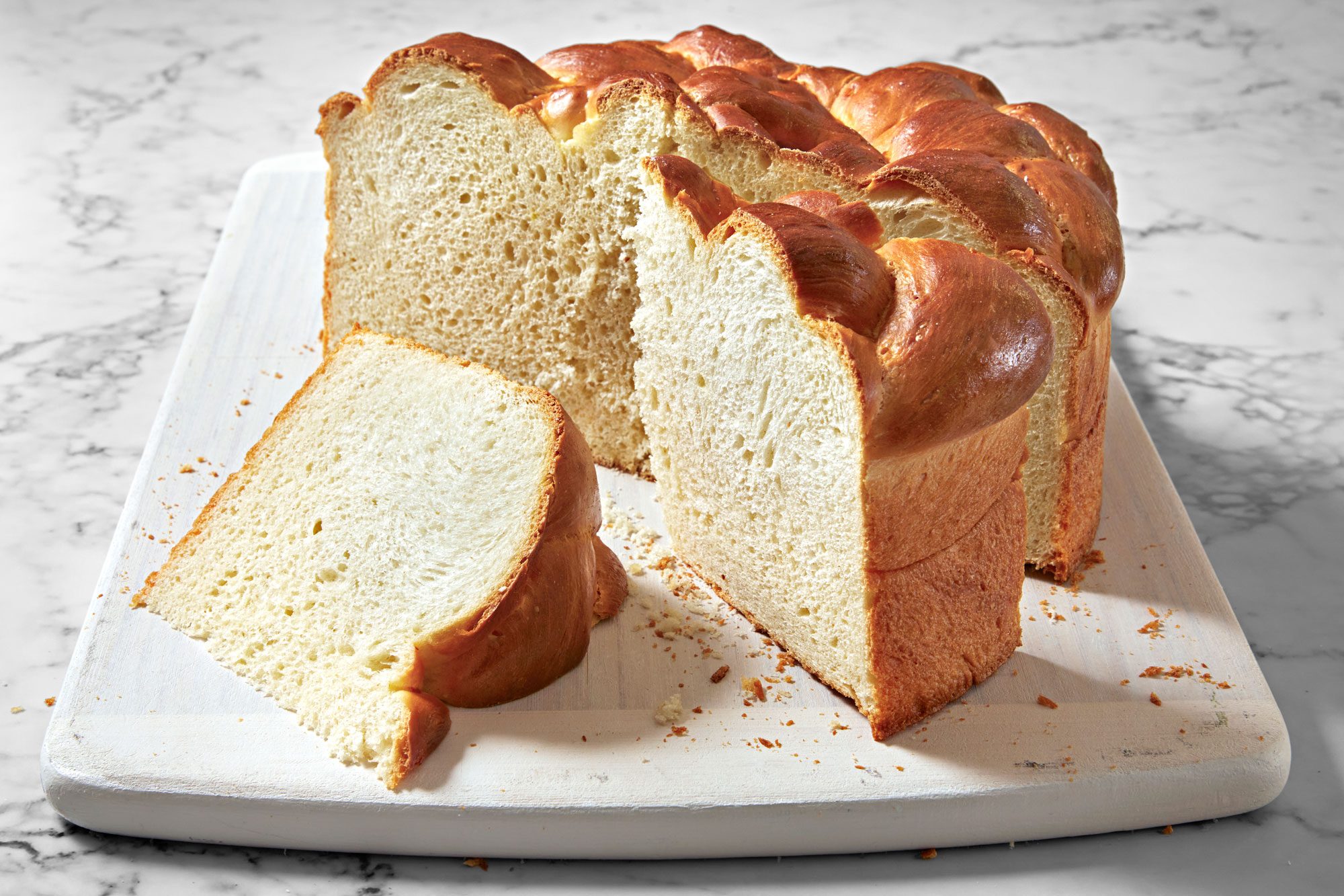 Table view shot of Paska Easter Bread; serve on wooden tray; cut into slices; marble surface