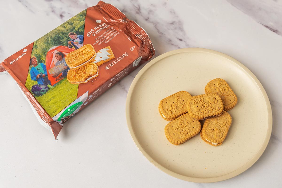 Package of S'mores Girl Scout Cookies next to several cookies on a plate